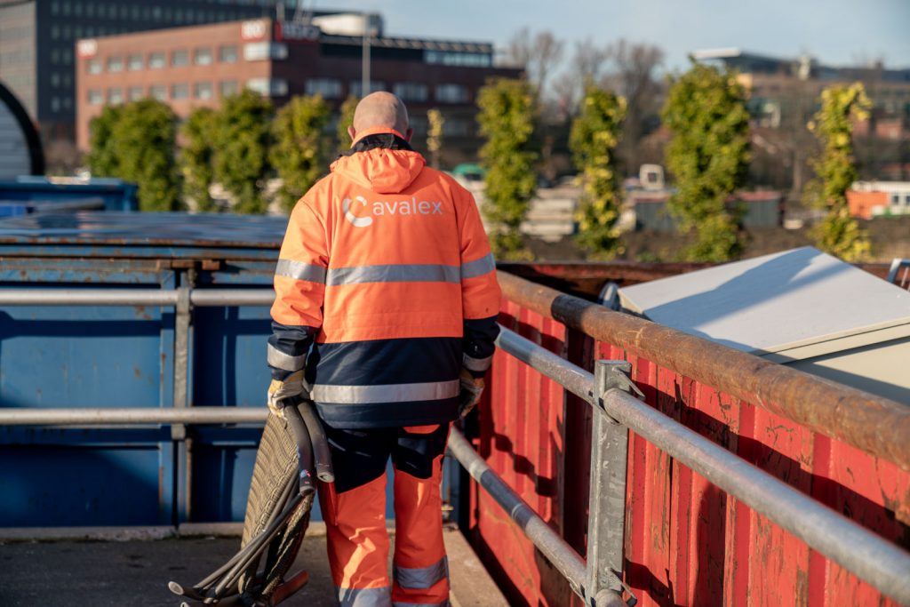 Medewerker van Avalex tilt een stoel op bij de milieustraat, klaar om deze weg te brengen voor verwerking.